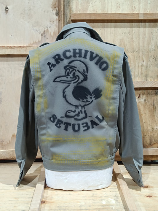 Gray jacket with yellow and black design on the back, featuring text and a logo, against a wooden background.