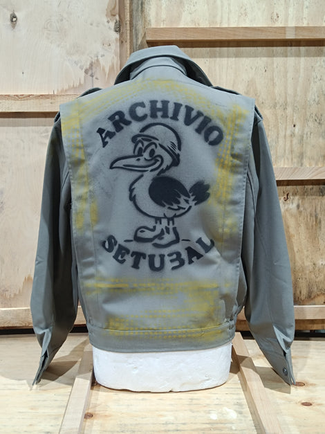 Gray jacket with yellow and black design on the back, featuring text and a logo, against a wooden background.